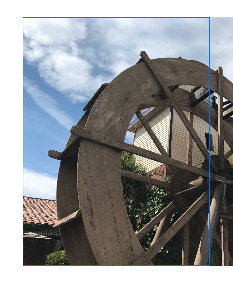 An image that shows a frame with a blue border overlaid on an image of a water wheel. The water wheel image fills its entire space vertically, and extends past the right edge of the frame horizontally.